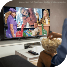 A New York Post image composite showing multiple Super Bowl ads is displayed on a TV. A woman watches while eating a bowl of popcorn.