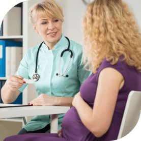 A pregnant woman sits at a table to talk to her doctor