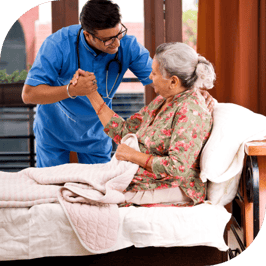 An elderly woman sits upright in bed with the assistance of a male nurse