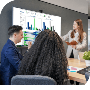 A group of business people at a conference table with a woman presenting data in the Tunnl platform