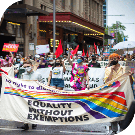 People in masks with flags and signs marching against discrimination