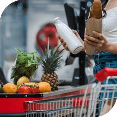 A woman is purchasing fresh produce, bread, and milk at a grocery store using SNAP benefits.