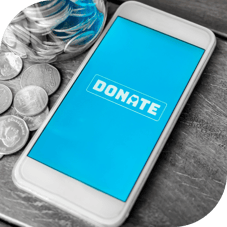 a phone with the word donate across it with a jar of coins on the table nearby
