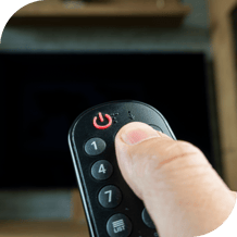 person holding a remote to turn off a TV