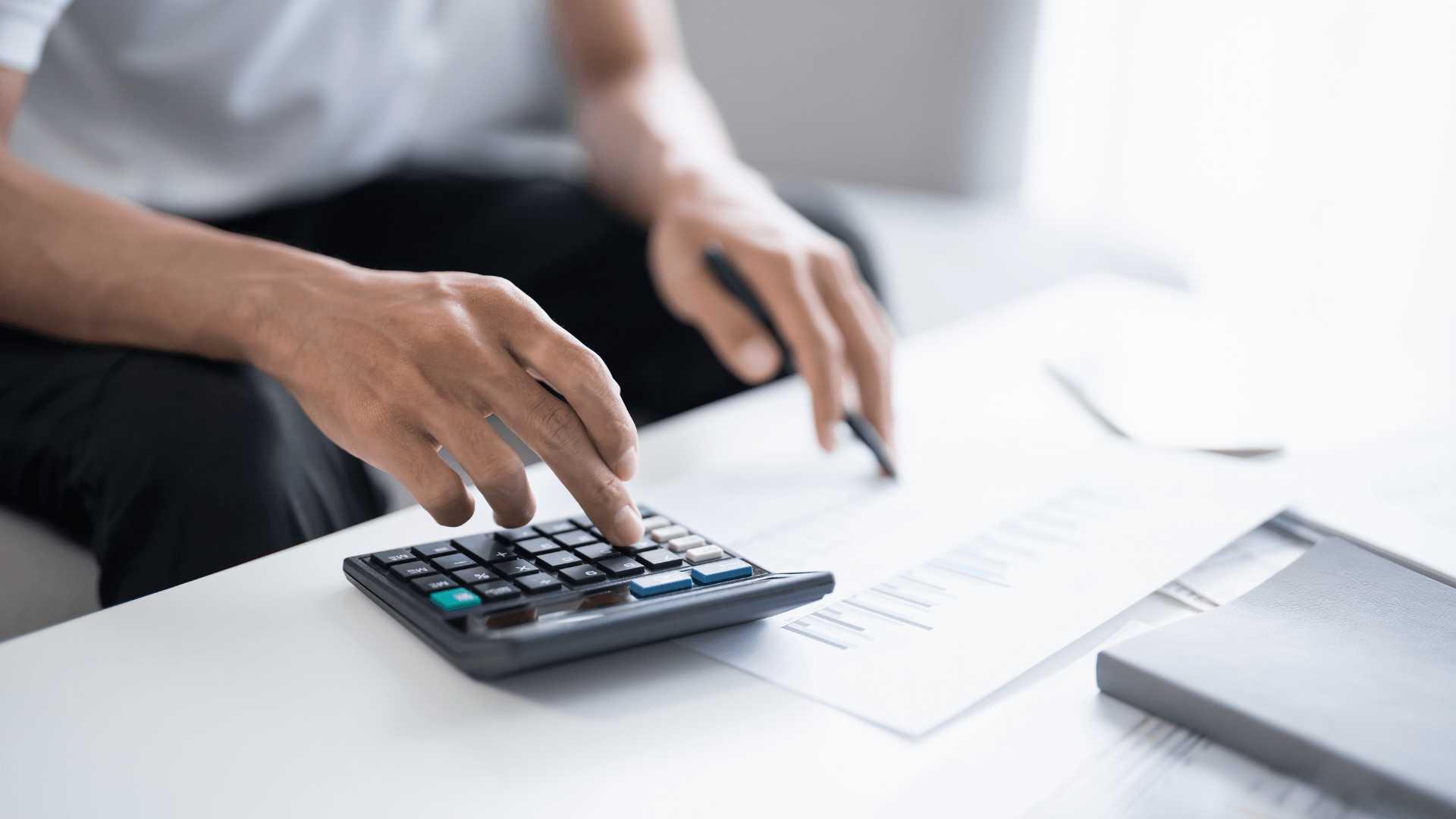 Photo of a man using calculator to add up bills 