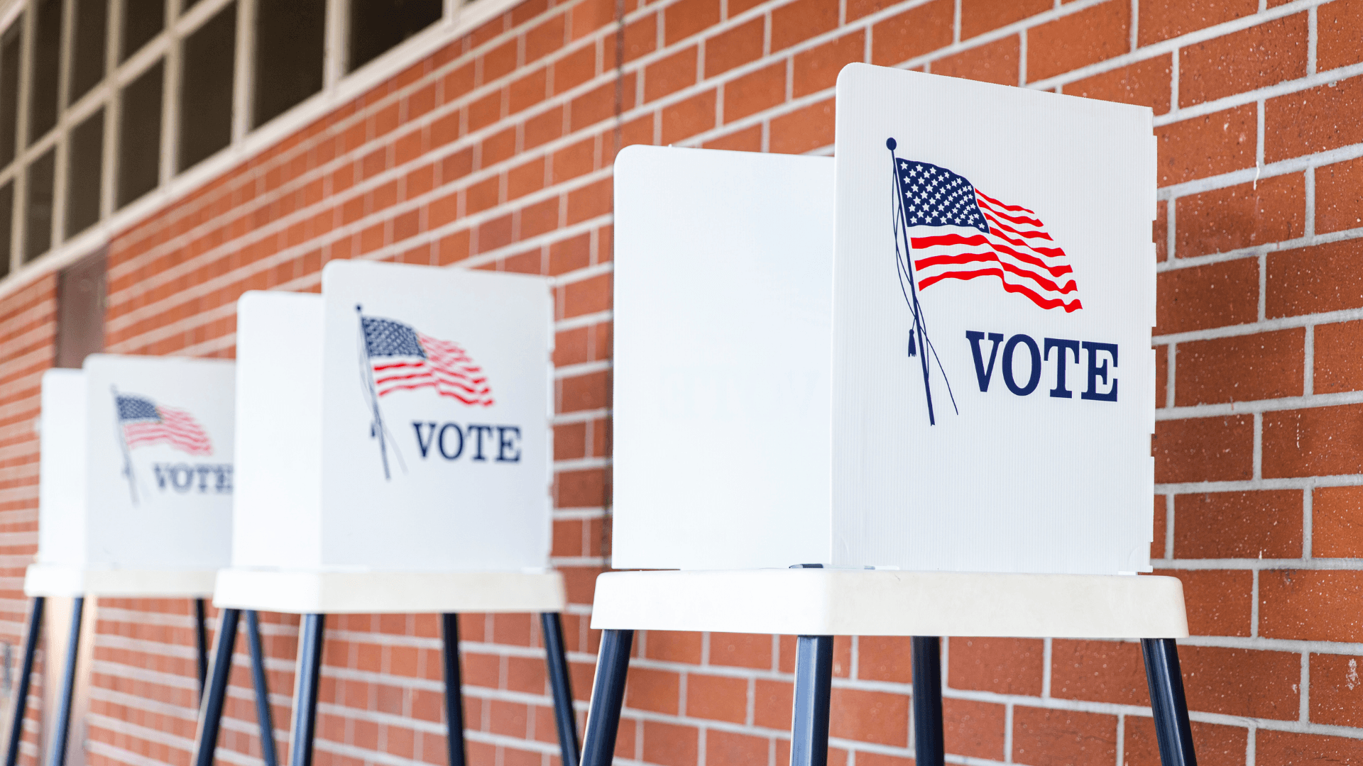 Photo of voting booths in front of a brick wall